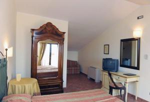 蒙蒂菲阿斯科尼尔巴诺伍酒店的一间卧室配有一张床和一张书桌及电视