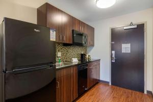 布里奇顿MainStay Suites St Louis Airport的厨房配有黑色冰箱和木制橱柜。