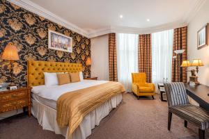 伦敦阿什本酒店的一间卧室配有一张床、一张桌子和一把椅子