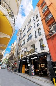 伊斯坦布尔Orka Taksim Suites & Hotel的一座高大的白色建筑,上面有商店的标志