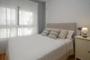 维戈Apartamento zona exclusiva garaje gratis y Netflix的卧室配有带枕头的白色床和窗户。