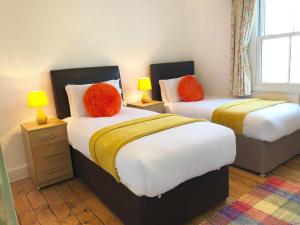 特鲁罗Feock beautiful sunny cottage的两张带红色枕头的床,位于客房内