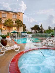 安纳海姆阿纳海姆艾雅酒店的一个带椅子的大型游泳池和一间酒店