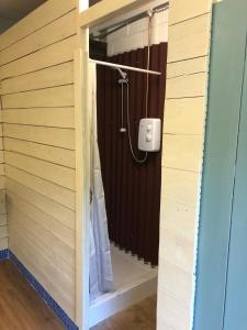 斯托马基特The Tawny Shepherd Hut, Whitehouse Farm的木制墙壁上带淋浴的浴室