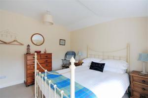 莱姆里吉斯Half Moon Cottage的卧室配有白色的床和梳妆台。