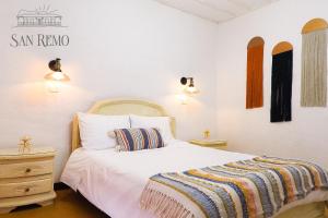 圣罗莎德卡瓦尔Hotel Rural SAN REMO的卧室配有白色的床,床上有条纹毯子