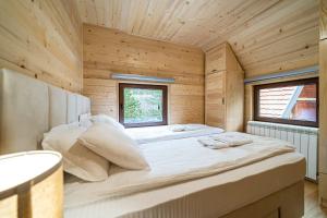 卡鲁德杰尔斯科巴尔Brvnara Ljubomir, planina Tara, Kaludjerske Bare的木制客房内的一张大床,设有窗户