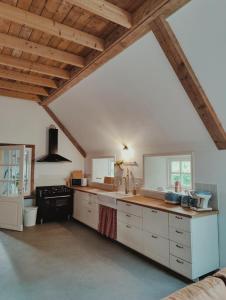 WolsumB & B Wijdzicht的一间设有白色橱柜和木制天花板的大厨房
