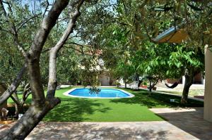 本科瓦茨Studio Apartments Luka Biograd - Benkovac的一座有树木和草地的庭院内的游泳池