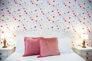 阿尔巴塔克斯B&B Calamoresca的卧室配有白色床,墙上挂着红色鲜花