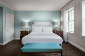 圣路易斯The Royal Sonesta Chase Park Plaza St Louis的一间卧室配有一张白色大床和蓝色长凳