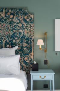 基督城The Observatory Hotel Christchurch的一间卧室配有一张床,墙上装饰着花卉图案的壁纸
