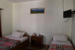 博卡拉Gurkha Lodge的小房间设有两张床和电视