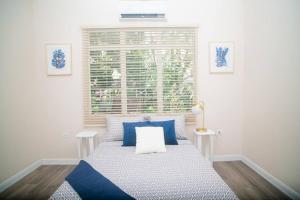 西班牙港RayneBow Chateau - Chic City Getaway的一间卧室配有一张带蓝色枕头的床和一扇窗户。