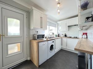 塞拉戴克Dragonfly - HOT TUB luxury two bedroom cottage的厨房配有白色橱柜、洗衣机和烘干机