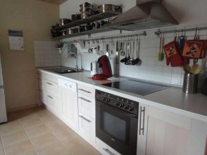 卡珀尔恩Ferienwohnung Hilde Schneider的厨房配有白色橱柜和黑炉灶烤箱。