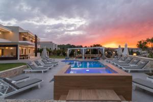 PeramaElaida Villa, Heaven on Earth, By ThinkVilla的日落时分带游泳池和躺椅的度假村