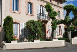 FeursL'Hôtel L'Astrée的前面有一棵树的粉红色房子