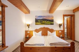 米滕瓦尔德桑嫩海姆宾馆的卧室配有一张大床,墙上挂有绘画作品
