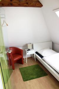曼海姆coLodging Mannheim - private rooms & kitchen的一间小卧室,配有一张床和一把红色椅子