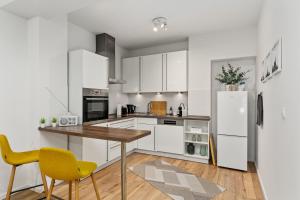 不莱梅City-Apartment direkt in den Parkanlagen的厨房配有白色橱柜、木桌和黄色椅子