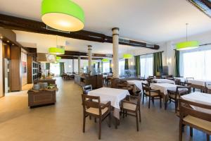 卡拉郫萨巴萨普拉纳酒店的餐厅设有白色的桌椅和窗户。