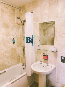 波士顿Boston West Hotel的浴室配有水槽、浴缸和淋浴帘