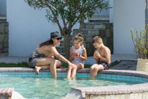 卡尼奥提Nikiforos Village的坐在游泳池旁的一名妇女和两名儿童