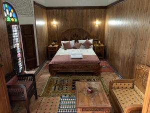 梅克内斯Riad Palais Marouane的卧室配有1张床、1张桌子和1把椅子
