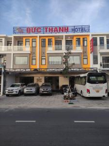 迪石ĐỨC THẠNH HOTEL的一座大型建筑,前面有汽车停放