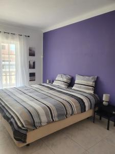 拉戈斯Brisa's Haven Guesthouse !Pet Friendly!的一间卧室配有一张紫色墙壁的床