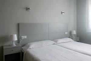 美洲海滩Apartamentos Angelito的一间卧室配有一张带白色床单和两盏灯的床。