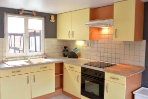 埃圭斯海姆Gite Géranium***的厨房配有黄色橱柜、水槽和炉灶。
