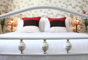 Rockbearethe grange boutique guest house的一张白色的床,上面有红色和黑色的枕头