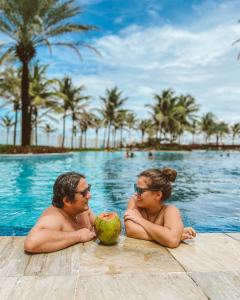 阿奎拉兹Golf Ville Resort Brisa do Golf -Apartamentos e Cobertura的坐在有椰子的游泳池里的男人和女人