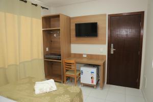 库尔韦卢Pontal Executive Hotel的小房间设有一张桌子、一张床和一台电视机
