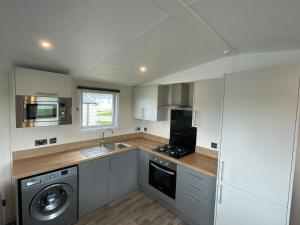普里茅斯Luxury 6 Bed Lodge with Hot Tub的厨房配有水槽、洗衣机和烘干机