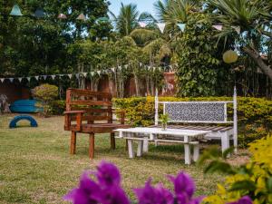 布希奥斯Numa Boa HOSTEL Búzios的院子里放着鲜花,放着两把长椅和一张桌子