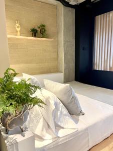 麦德林beminimal Hotel的卧室配有白色的床和盆栽植物