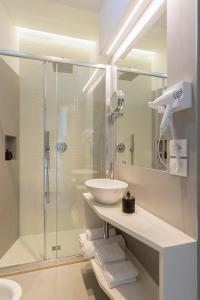 里乔内康莫多雷酒店的白色的浴室设有水槽和淋浴。