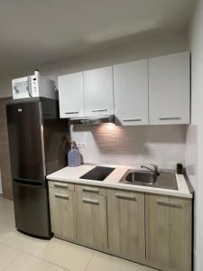 曼德雷Apartmani Pernjak的厨房配有白色橱柜和黑色冰箱。