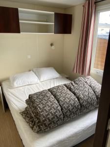 Biville-sur-MerCamping le Clos Savoye的卧室内的一张床铺,带窗户