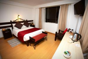 库斯科Koyllur Inn的一间卧室配有一张大床,铺有红白毯子