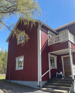 BjurholmSurrounded by nature in Bjurholm的坐在红房子前廊的女人