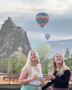 格雷梅本地岩洞酒店的两名妇女,配上酒杯和热气球