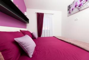 奇茲希App Kokotić的一间卧室配有一张粉红色的床、紫色床单和枕头