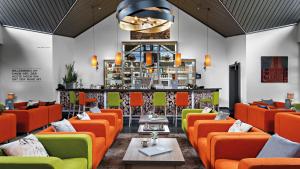 奥尔珀Hotel Diehlberg的一间设有橙色和绿色椅子的餐厅和一间酒吧