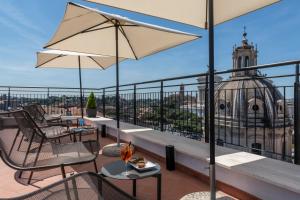 罗马H10 Palazzo Galla的阳台配有桌椅,享有建筑的景致。