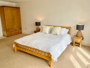 赫尔姆斯利Rye Court Cottage - Stunning cottage in central Helmsley with parking的一间卧室配有一张大床,桌子上放着两盏灯