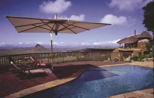 HlazakaziIsandlwana Lodge的游泳池配有遮阳伞、椅子、桌子和椅子